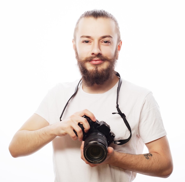 Concepto de estilo de vida, tecnología y viajes hombre barbudo con camiseta blanca con una cámara digital aislada sobre un fondo blanco