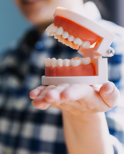 Concepto de estomatología retrato parcial de niña con dientes blancos fuertes mirando a la cámara y dedos sonrientes cerca de la cara Primer plano de una mujer joven en el estudio del dentista en el interior