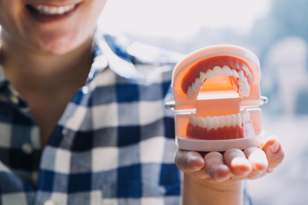 Concepto de estomatología retrato parcial de niña con dientes blancos fuertes mirando a la cámara y dedos sonrientes cerca de la cara Primer plano de una mujer joven en el estudio del dentista en el interior