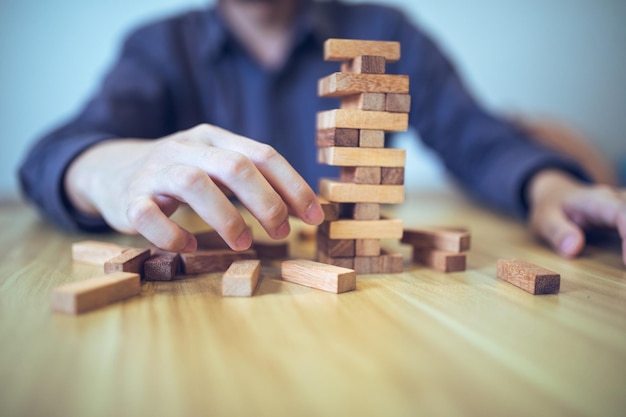 Concepto de estrategia de negocios con las manos jugando a un juego de torre de bloques de madera Planificación gestión de riesgos