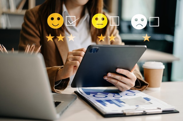 Concepto de evaluación del servicio al cliente Empresaria presionando la cara sonrisa emoticono mostrar en la pantalla virtual en la tableta y el teléfono inteligente