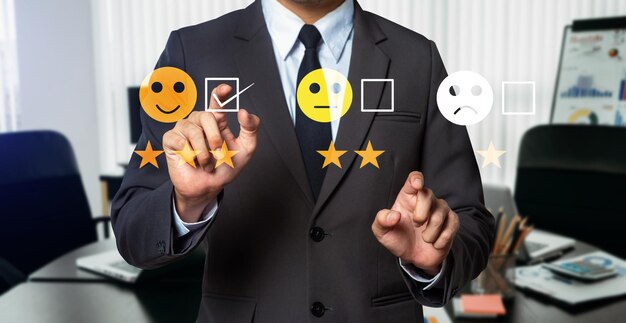 Concepto de evaluación del servicio al cliente Empresario presionando el espectáculo de emoticonos de sonrisa en la pantalla virtual en la tableta y el teléfono inteligente en la oficina modernaxA