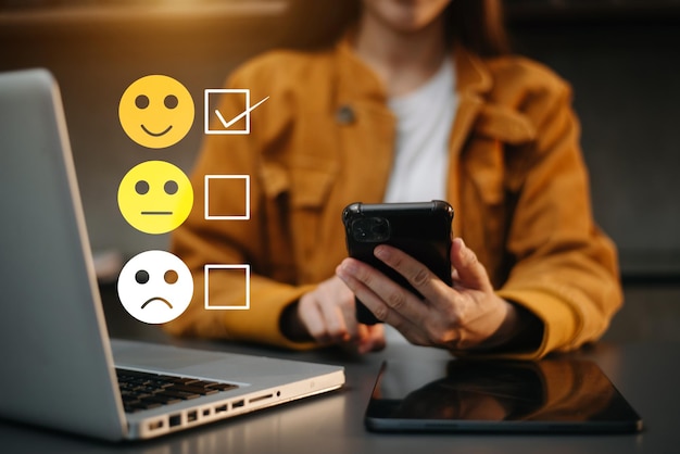 Concepto de evaluación del servicio al cliente Mujer Mostrar emoticono de sonrisa en la pantalla virtual desde la mano mirando la tableta del teléfono inteligente y la computadora portátil