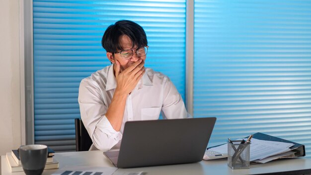 Concepto de exceso de trabajo El empleado sentado en la oficina y bostezando en su escritorioxA