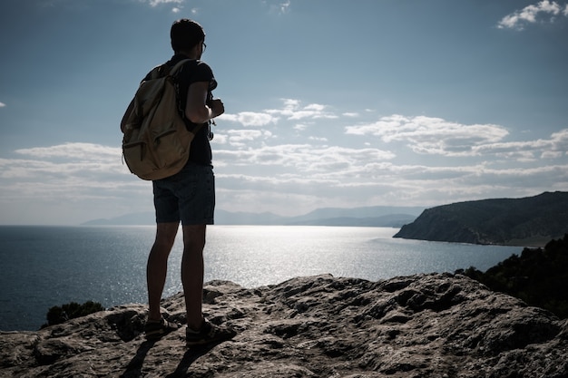 Concepto de éxito. Caminante con mochila de pie en la cima de una montaña con las manos levantadas y disfrutando de la vista