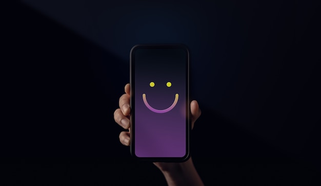 Concepto de experiencias del cliente. Mano sosteniendo un teléfono móvil con emoticon de cara sonriente. Cliente feliz dando una valoración positiva de la revisión. Encuestas de satisfacción del cliente