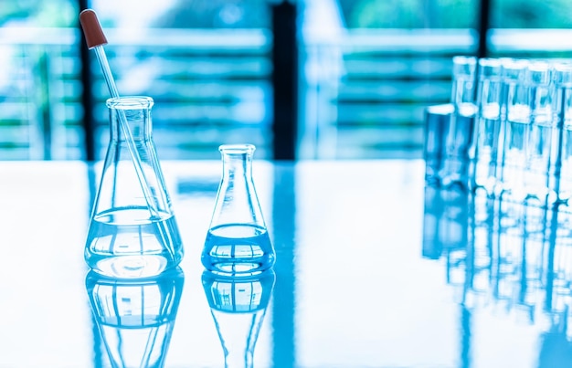 Foto concepto de experimento de química en laboratorio de ciencias dos matraces científicos de diferentes tamaños contienen diferentes productos químicos en un escritorio blanco nadie copia espacio a la derecha para el diseño fondo borroso cerrar