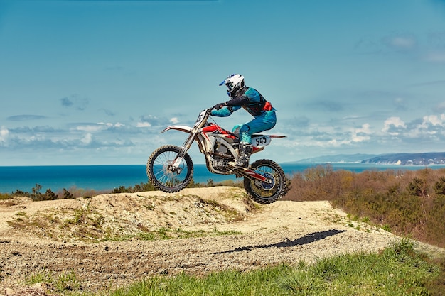 Concepto extremo, desafíate a ti mismo salto extremo en una motocicleta sobre un cielo azul con nubes