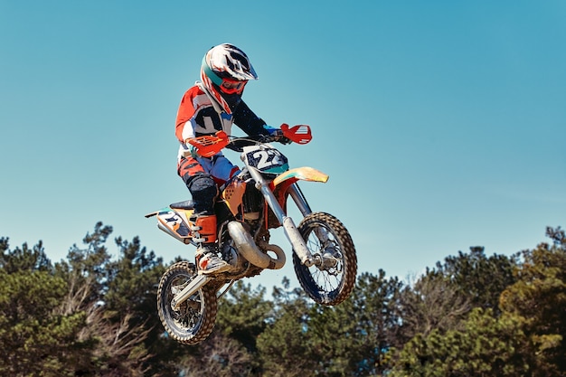 Concepto extremo desafíate a ti mismo Salto extremo en una motocicleta sobre un fondo de cielo azul con nubes Copie el espacio todo o nada