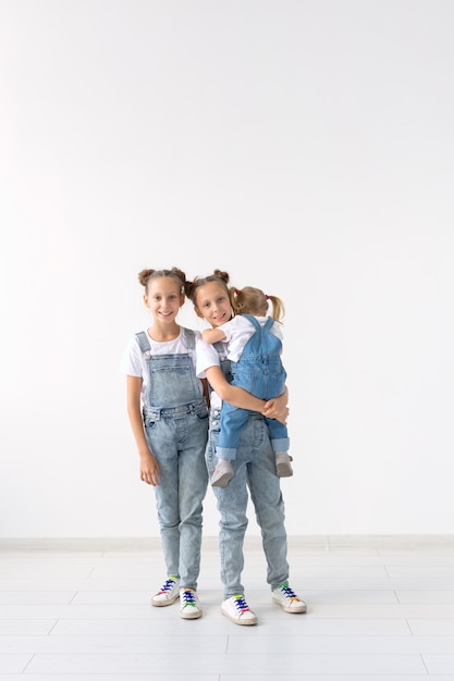 Concepto de familia y amor - Tres hermanas abrazándose sobre fondo blanco.