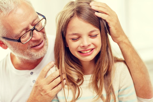 concepto de familia, apoyo, infancia y personas - abuelo con nieta llorando en casa