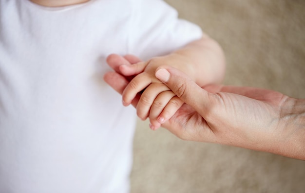 concepto de familia, caridad y personas - cierre de manos de bebé y madre