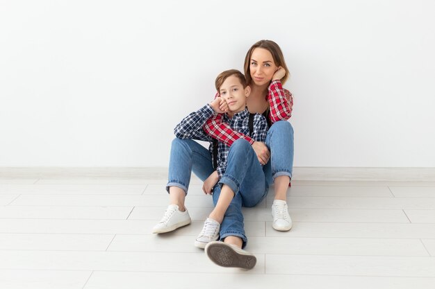 Concepto de familia, día de la madre y adolescente - Retrato de madre e hijo sentados en el suelo