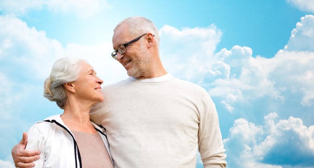 concepto de familia, edad, amor, relaciones y personas - feliz pareja mayor sobre el cielo azul y el fondo de las nubes