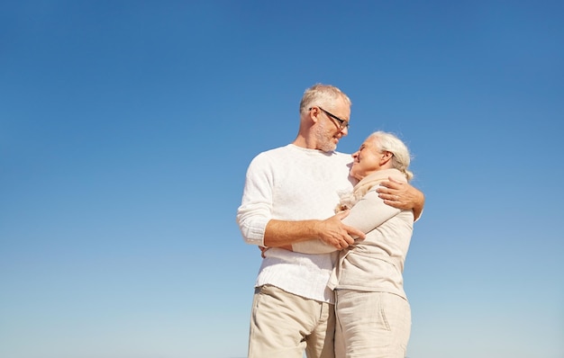 concepto de familia, edad y personas - feliz pareja mayor hablando al aire libre