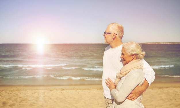 concepto de familia, edad, viajes, turismo y personas - feliz pareja de ancianos caminando por la playa de verano