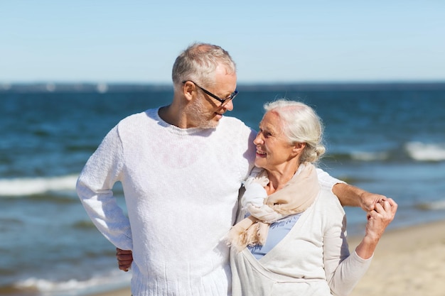 concepto de familia, edad, viajes, turismo y personas - feliz pareja mayor abrazándose en la playa de verano