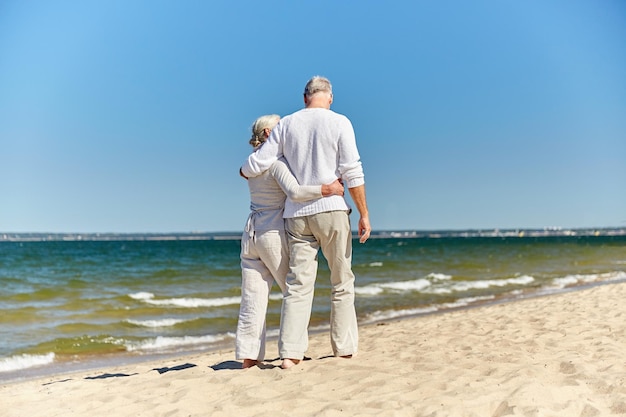 concepto de familia, edad, viajes, turismo y personas - feliz pareja mayor abrazándose en la playa de verano