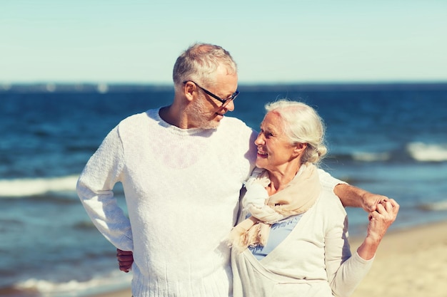 concepto de familia, edad, viajes, turismo y personas - pareja de ancianos felices abrazándose en la playa de verano