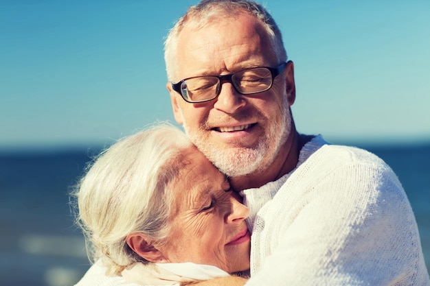 concepto de familia, edad, viajes, turismo y personas - pareja de ancianos felices abrazándose en la playa de verano