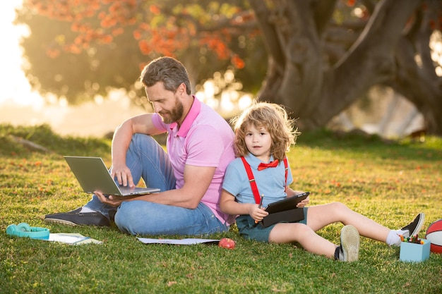 Concepto de familia elearning padre e hijo con tablet PC afuera en el parque