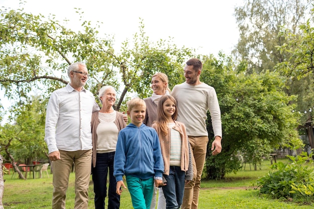 concepto de familia, felicidad, generación, hogar y personas - familia feliz parada frente a la casa al aire libre