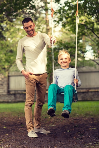 concepto de familia, felicidad, generación, hogar y personas - feliz padre e hijo balanceándose en el teeterboard al aire libre