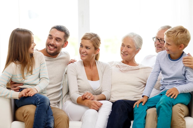 Concepto de familia, felicidad, generación y personas - familia feliz sentada en el sofá en casa