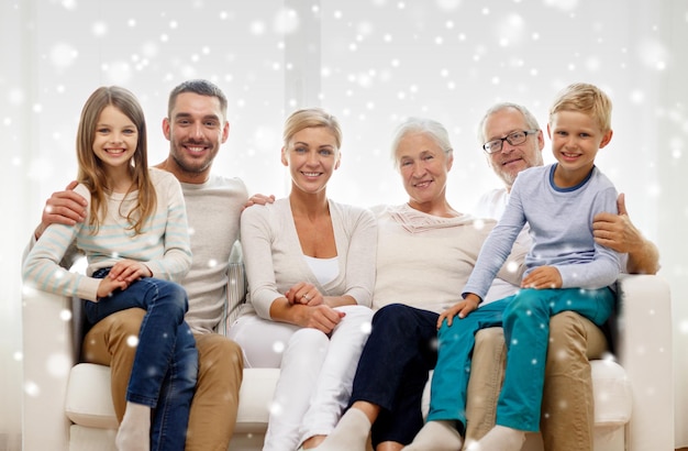 Concepto de familia, felicidad, generación y personas - familia feliz sentada en el sofá en casa