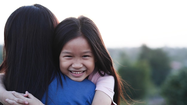Concepto de familia feliz Closeup retrato feliz niño asiático niña abrazo o madre abrazando