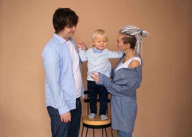 Concepto de familia feliz. Madre y padre e hijo pequeño aislado en la pared beige