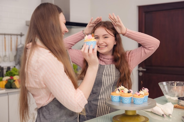 Foto el concepto de familia feliz de una madre y su hija disfrutando de pasteles juntos en la cocina de casa