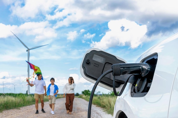 Concepto de familia feliz progresiva en aerogenerador con vehículo eléctrico