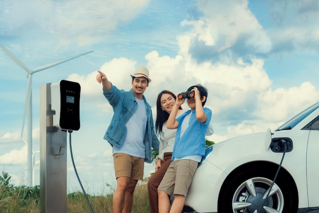 Concepto de familia feliz progresiva en un parque eólico con vehículo eléctrico