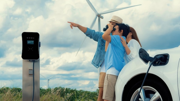 Concepto de familia feliz progresiva en un parque eólico con vehículo eléctrico