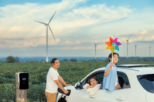 Concepto de familia feliz progresiva en un parque eólico con vehículo eléctrico