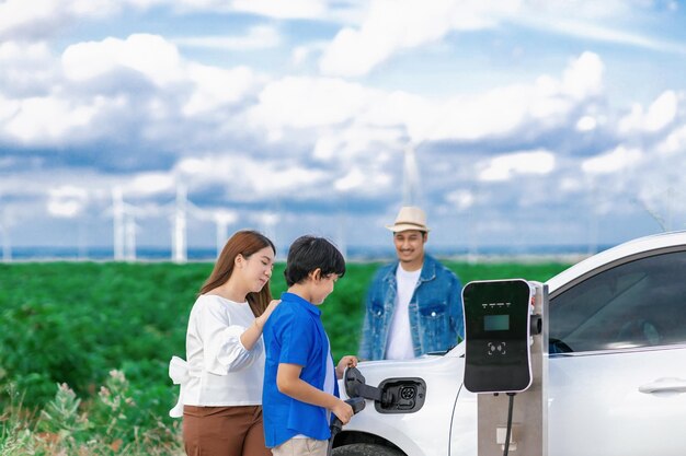 Concepto de familia feliz progresiva en un parque eólico con vehículo eléctrico