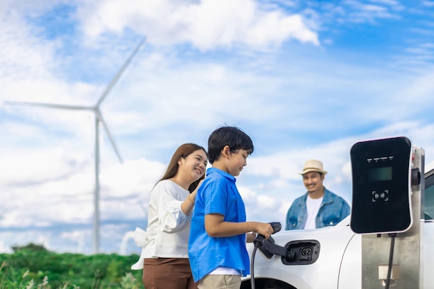 Concepto de familia feliz progresiva en un parque eólico con vehículo eléctrico