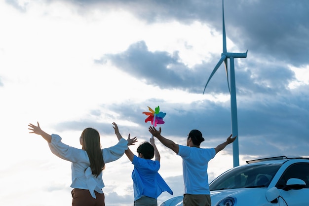 Concepto de familia feliz progresiva en un parque eólico con vehículo eléctrico