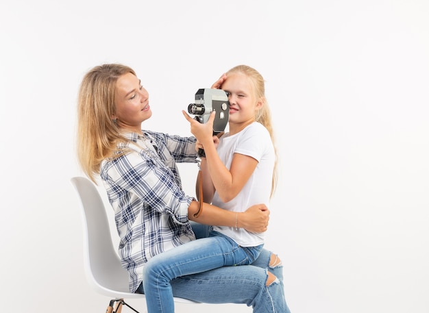 Concepto de familia, fotografía y afición - mujer y su hijo con una cámara antigua sobre fondo blanco.