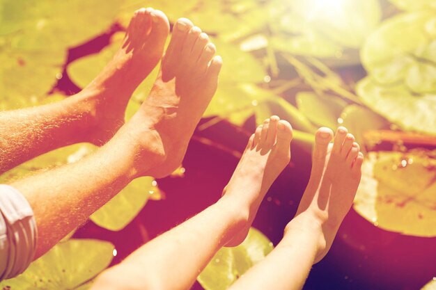 Foto concepto de familia, generación y pueblo - abuelo y nieto pies sobre el río