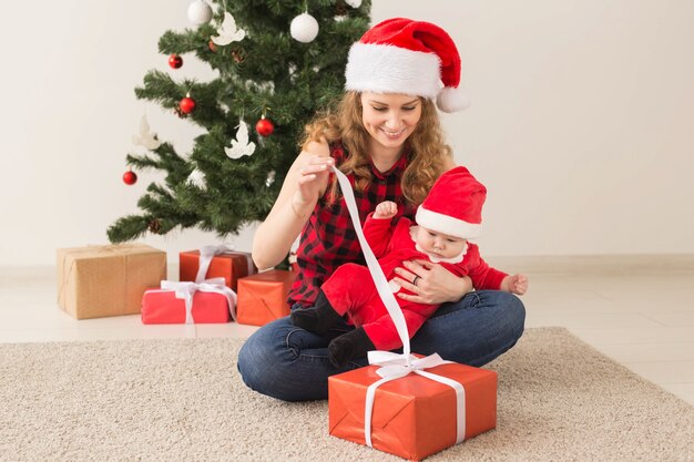 Concepto de familia, infancia y Navidad - Retrato de madre feliz y adorable bebé en traje de Santa.