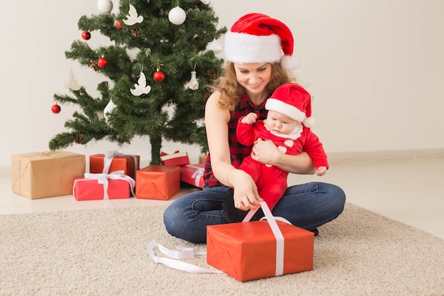 Concepto de familia, infancia y Navidad - Retrato de madre feliz y adorable bebé en traje de Santa.