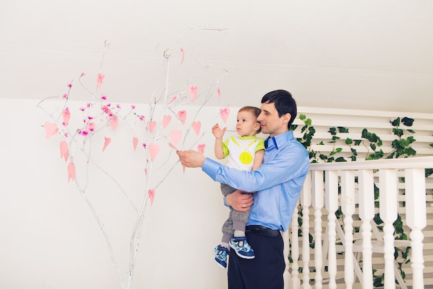 Concepto de familia, infancia, paternidad, actividad y personas - padre feliz e hijo pequeño jugando en casa.