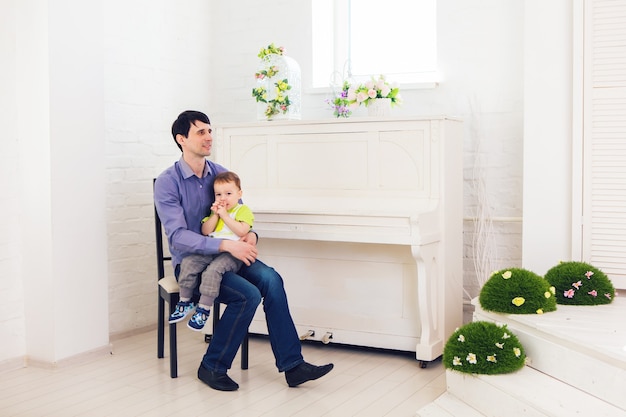 Concepto de familia, infancia, paternidad, actividad y personas - padre feliz e hijo pequeño jugando en casa.