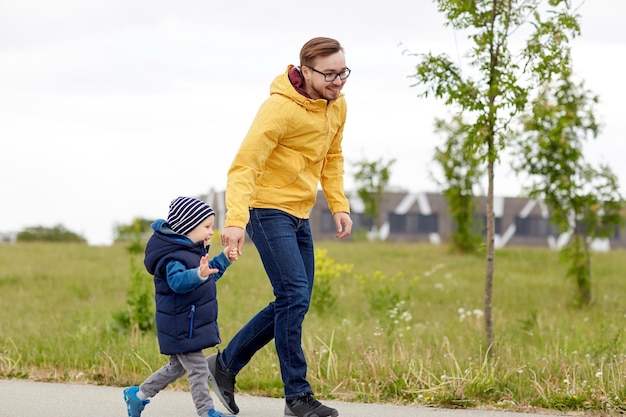 concepto de familia, infancia, paternidad, ocio y personas - padre feliz e hijo pequeño caminando al aire libre