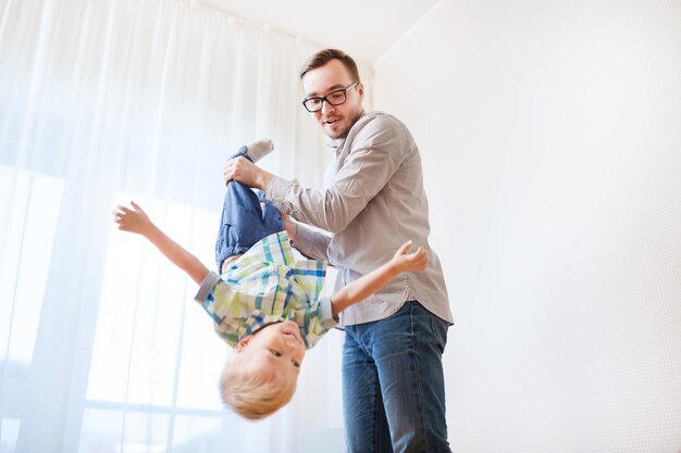 concepto de familia, infancia, paternidad, ocio y personas - padre feliz e hijo pequeño jugando y divirtiéndose en casa