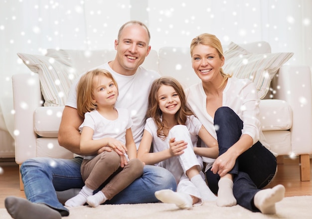 concepto de familia, infancia, personas y hogar - padres sonrientes con dos niñas pequeñas sentadas en el suelo en casa