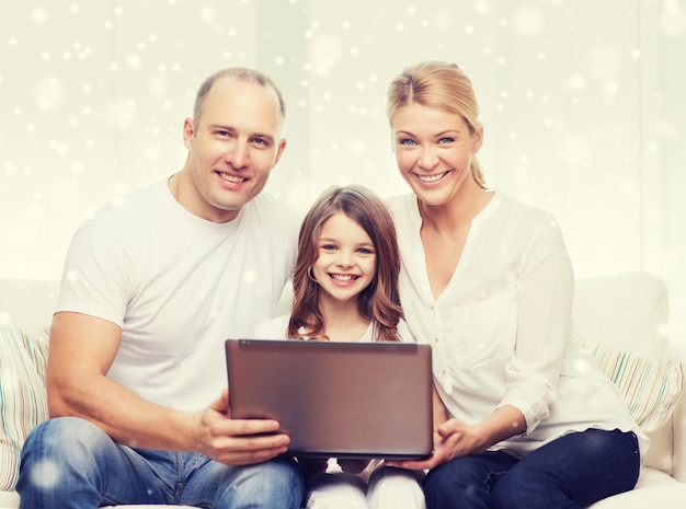 Foto concepto de familia, infancia, tecnología y personas - familia sonriente con computadora portátil sobre fondo de copos de nieve