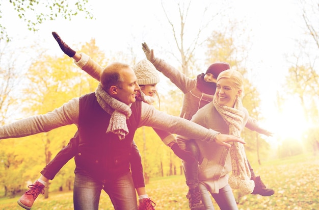 concepto de familia, infancia, temporada y personas - familia feliz divirtiéndose en el parque de otoño